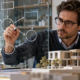 Researcher mapping a theoretical model beside a construction scale model