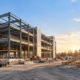 Commercial steel-frame building and wood-framed house under construction side by side.