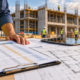 Quantity surveyor checks a bill of quantities against architectural plans and tender costs on an active construction site