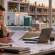 A project manager reviews site-office, temporary utility, and safety supply expenses while construction work continues outside.