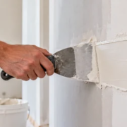 13270-feature-image Finisher spreads construction putty over a wall patch to create a smooth surface for finishing.