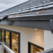 Roof gutter fitted with a debris guard directing rainwater through a downspout to safe drainage away from the foundation.