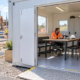 Construction workers use a clean site welfare cabin with handwashing, drinking water and rest seating beside a portable toilet and active build site.