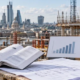 A quantity surveyor checks a construction cost reference book and benchmark chart against plans and material samples at a London building site.
