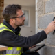 Building surveyor checks an existing concrete block wall as part of a mundic-block durability assessment.