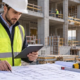 Quantity surveyor measuring construction quantities on plans at an active building site