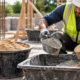 Mason measures separate cement and sand loads before mixing mortar at a construction site