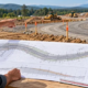 Civil engineer compares road construction plans with the marked alignment and graded roadway on site