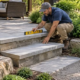A contractor levels a two-step garden stair between a patio and landscaped path while an architect checks the landing transition.
