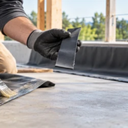 15563-feature-image Builder checks the tack of a thin rubber cement coat before bonding a rubber sheet