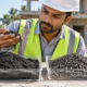 Materials engineer examines black sand and graded aggregate samples before selecting material for house construction