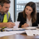 Construction estimator and accountant reviewing commercial building invoices and tax records