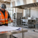 Contractor measuring plans for a stainless steel commercial kitchen fit-out