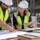 Construction managers compare material quantities and building plans on a jobsite to control commercial construction costs.