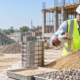Engineer checks a construction sand sample beside a sieve stack and aggregate piles to assess grading and material quality.