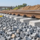 Construction engineer inspects crushed stone ballast supporting railway sleepers and rails