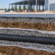 Perforated underdrain pipe in gravel and filter fabric below paving, connected to an inspection manhole.