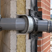 Engineers check a sleeved pipe penetration through a masonry wall and its exterior seal.