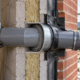 Engineers check a sleeved pipe penetration through a masonry wall and its exterior seal.