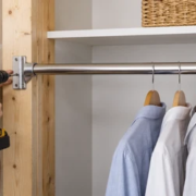 Carpenter secures a closet rod support bracket to wall framing before the pole carries hanging clothes.