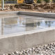 Raised concrete rim forms a border around a slab as a worker checks it with a level