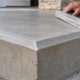 Concrete finisher checks a beveled chamfered edge on a newly formed concrete step.