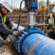 Technicians using a controlled tapping machine and saddle to create a new branch connection on an existing water main.