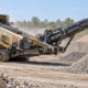 Mobile scalping screen separates oversized rock from graded aggregate at a construction materials site.