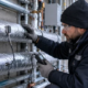 A plumber checks insulation and temperature probes on hot and cold water lines in a cold commercial service area.