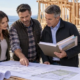 A homeowner, builder, and lender representative review a construction loan budget beside a house under construction.