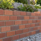A mason measures the one-third offset between brick courses on a running bond wall while a supervisor checks alignment.