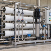 A water-treatment engineer checks gauges, controls and a treated-water sample beside a construction-site reverse osmosis system.
