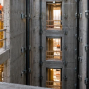 A surveyor checks elevator shaft alignment as crews build the concrete core and prepare landing openings for elevator rails.