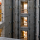 A surveyor checks elevator shaft alignment as crews build the concrete core and prepare landing openings for elevator rails.