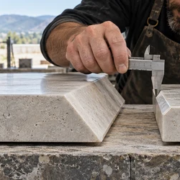 21619-feature-image A stone fabricator compares a broad beveled edge with a smaller chamfered edge on matching countertop samples using a profile gauge and caliper.