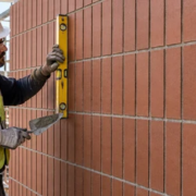 Mason checking the straight vertical joints in a stack bond brick wall