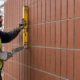 Mason checking the straight vertical joints in a stack bond brick wall