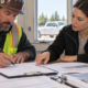 A subcontractor verifies an invoice and lien release form with a general contractor accounts manager before signing.