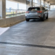 A civil engineer reviews a parking garage vehicle ramp with a textured surface, drainage channel, protective curb, and separate pedestrian path.