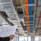 MEP engineer reviews coordinated HVAC ducts, electrical conduit, and plumbing pipes in an open ceiling.