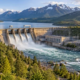 Dam releases water into a river from a reservoir beside an irrigation channel and forested watershed.