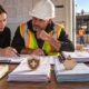 A payroll accountant and superintendent review base labor hours, benefits, insurance, and payroll records for a construction crew.
