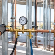 A plumbing technician monitors a pressure gauge during a water pipe test before the walls are closed.