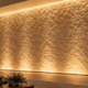 Modern stone feature wall evenly illuminated by concealed linear wall washer lights, with a lighting designer inspecting the effect.