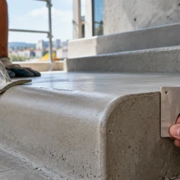 Mason shapes a rounded concrete stair edge with a radius gauge to show the smooth curve that replaces a sharp corner.