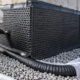 A site inspector checks dimpled drainage board meeting a gravel-wrapped foundation drain before backfill.