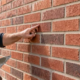 Mason pointing out staggered brick joints in a running bond wall