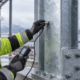 Inspector checks the thickness of galvanized coating on a steel column at a coastal construction site.