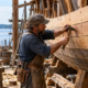 Shipwright fastens timber planks to a wooden boat hull during ship construction.