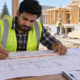 Estimator measures building plans with a scale and pencil to calculate construction material quantities at a residential jobsite